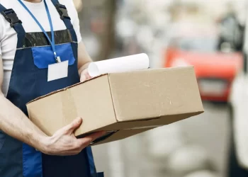 Entregador de encomendas segurando caixa nas mãos