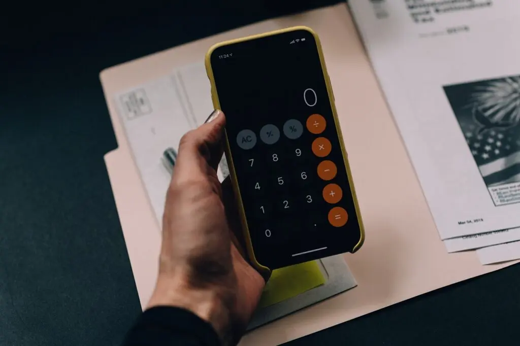 Mão segurando celular com aplicativo de calculadora aberto