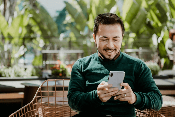 homem olhando sorrindo para o smartphone