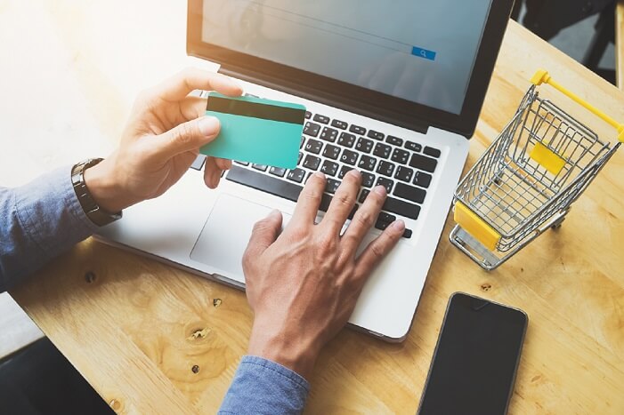 mãos de um homem segurando um cartão de crédito e trabalhando em um notebook