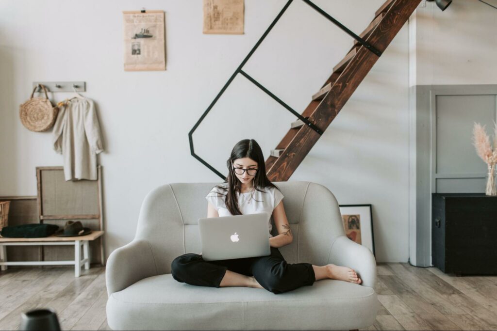 Mulher sentada em sofá utilizando um laptop