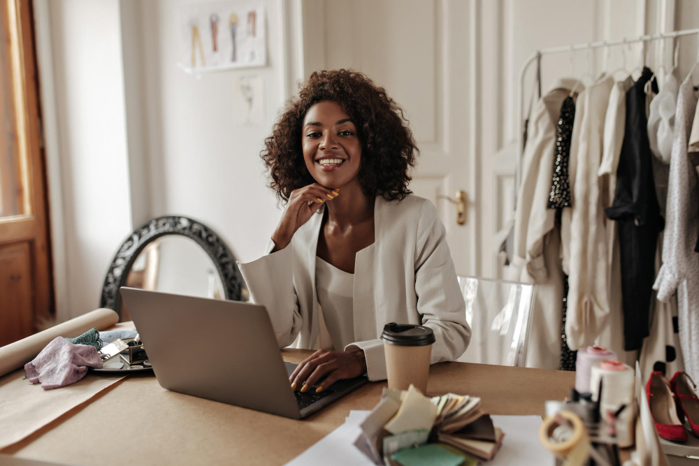 Mulher negra sentada sorrindo em frente laptop
