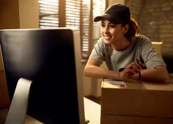 vendedora sorrindo com pacote pronto para postagem