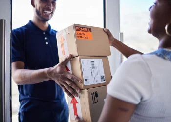 Entregador sorridente entregando encomendas para cliente, representando o frete Curitiba com entregas rápidas e seguras