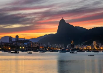 Vista do entardecer no Rio de Janeiro com o Cristo Redentor ao fundo e embarcações na Baía de Guanabara, representando o frete no Rio de Janeiro.