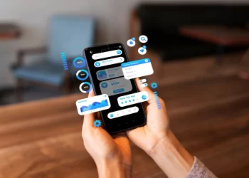 Pessoa usando aplicativo de controle de estoque multicanal no celular, com gráficos de desempenho e painel de gestão de produtos.