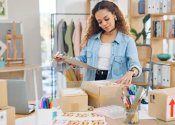 Empreendedora organizando o packing de pedidos em loja virtual com caixas e etiquetas