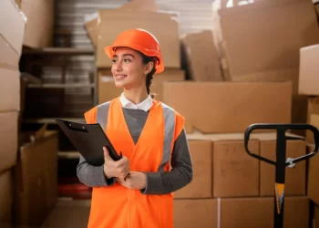 Mulher com prancheta na mãe em um centro logístico representando a operação de intermediadores de frete como Melhor Envio e SuperFrete