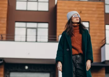 Mulher vestida de casaco, gorro e óculos escuro