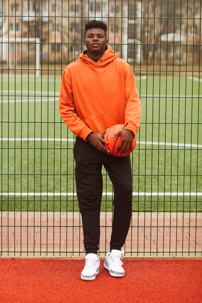Homem negro vestindo streetwear segurando bola de basketball