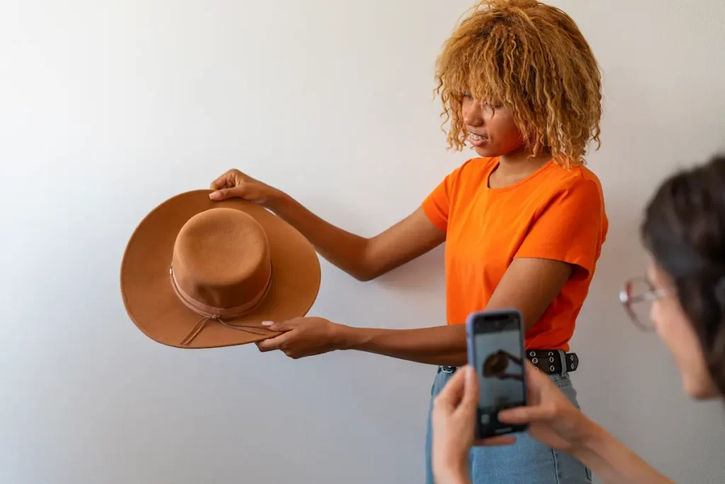 Mulher negra segurando chapéu para ser fotografado