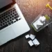 Laptop ao lado de um mini carrinho de compras com caixas